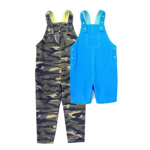Puede incluir: Dos pantalones de peto, uno con estampado de camuflaje y otro en azul sólido. Ambos tienen costuras amarillas y tirantes ajustables.