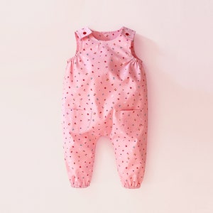 May include: Pink baby dungarees with a floral print and two pockets.