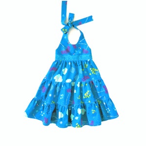 May include: A blue halter dress with a floral print and a tiered skirt. The dress has a tie at the neck and a white elastic waistband.