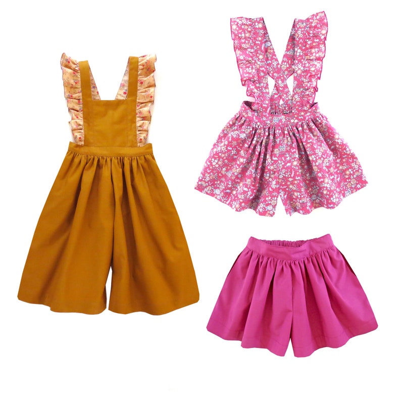 May include: Three different styles of girls' overalls. The first is a mustard yellow overall with a floral print ruffle trim. The second is a pink floral print overall with a ruffled strap. The third is a solid pink overall.