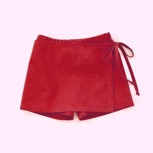 May include: A red wrap skirt with a tie closure. The skirt is made of a soft, lightweight fabric.