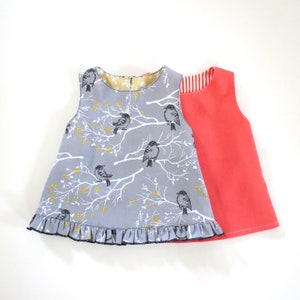 Peut inclure: Une robe sans manches grise avec un ourlet à volants et un imprimé d'oiseaux noir et blanc. La robe est superposée à une robe sans manches corail unie.