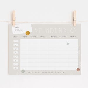 May include: A grey and white printable school timetable with the German word "Stundenplan" at the top. The timetable is divided into eight rows for periods and five columns for days of the week. The days of the week are labelled in German: Montag, Dienstag, Mittwoch, Donnerstag, Freitag. The timetable also includes a space for the student's name, class, and school.