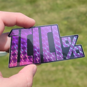 May include: A holographic sticker with the text "100%" in a black font with a purple and blue iridescent background.