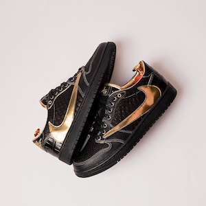 Peut inclure: Une paire de baskets noires et dorées. Les chaussures présentent une base noire avec des accents dorés, notamment le logo swoosh emblématique. Le design intègre des motifs texturés et une esthétique élégante et moderne. Les baskets sont posées sur un fond blanc.