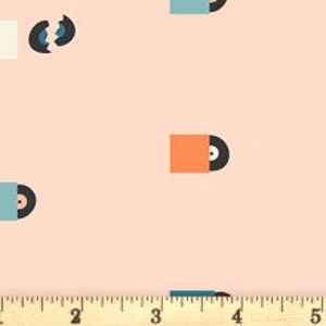 May include: A light pink fabric with a repeating pattern of vinyl records in their sleeves. The records are black, and the sleeves are various colors, including orange, blue, and cream. A ruler is at the bottom, showing inches.
