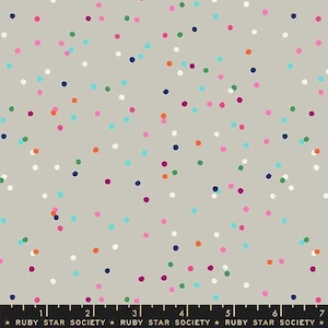 May include: A grey fabric with a confetti pattern of small, colourful dots. The dots are in shades of pink, blue, green, orange, red, and purple. The fabric is marked with a ruler in inches and the text "RUBY STAR SOCIETY".