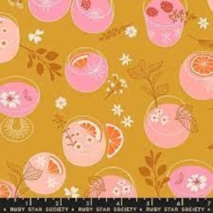 May include: A mustard yellow fabric with a repeating pattern of pink glasses filled with fruit and flowers. The glasses are outlined in brown and have a white rim. The background is a solid mustard yellow.