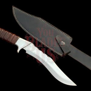May include: A silver and brown hunting knife with a serrated blade and leather-wrapped handle, next to a black leather sheath. The knife has a curved blade and a silver bolster.