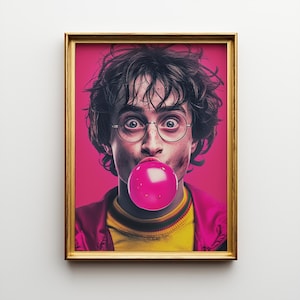May include: A framed print featuring a portrait of a person with round glasses blowing a large pink bubble. The person is wearing a yellow shirt with green and yellow stripes and a pink jacket. The background is a solid pink color.
