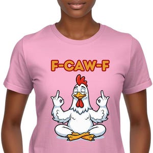 May include: A pale pink t-shirt with a cartoon chicken in a yoga pose, giving the middle finger. The text "F-CAW-F" is above the chicken. The chicken is white with a red comb and yellow beak and feet.