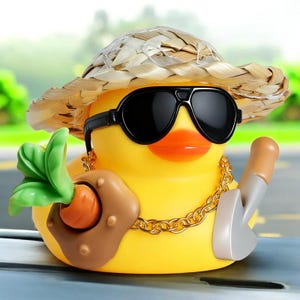 Könnte beinhalten: Eine gelbe Gummiente mit schwarzer Sonnenbrille, Strohhut und goldener Halskette. Die Ente hält eine Karotte und eine kleine Schaufel. Die Ente hat einen orangefarbenen Schnabel.