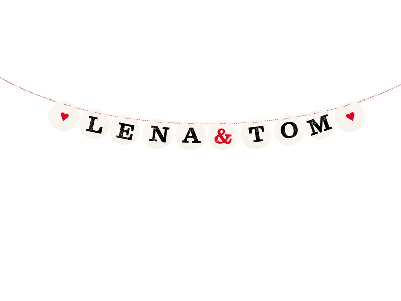 May include: A white banner with red hearts and black letters spelling "Lena & Tom" hanging on a red string.