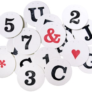 May include: A set of 14 round white paper tags with black and red lettering. The tags feature letters, numbers, and symbols, including an ampersand, a heart, and an asterisk.