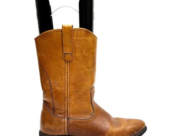 May include: A pair of brown leather cowboy boots with a pointed toe and a low heel.