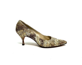 May include: A pair of gold and brown high-heeled shoes with a floral pattern.