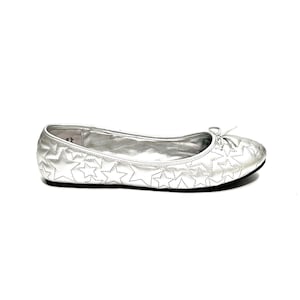 May include: Silver ballet flat with a star pattern stitched across the top. The shoe has a small bow detail at the toe and a black sole. The shoe is designed for comfort and style.