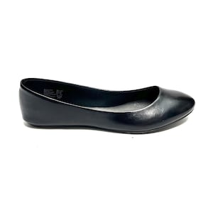 May include: A single black ballet flat shoe. The shoe has a rounded toe and a low heel. The material appears to be smooth and shiny. The shoe is set against a white background.