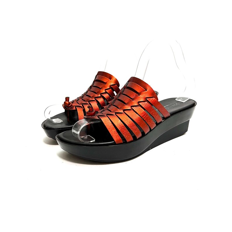 May include: A pair of orange leather sandals with a woven design and a black platform wedge heel.