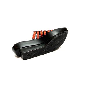 May include: A pair of brown leather wedge sandals with a black sole. The sandals have a criss-cross strap design.