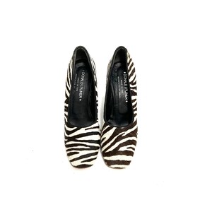 Pode incluir: Um par de sapatos de salto alto com estampa de zebra em preto e branco com bico quadrado. Os sapatos s&atilde;o feitos na It&aacute;lia por Donald J Pliner.