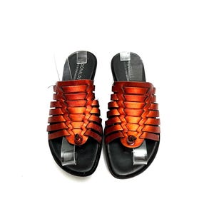 May include: A pair of orange leather sandals with a woven design. The sandals have a black sole and a small metal accent on the toe strap. The brand name "DONALD J" is printed on the side of the sandals.