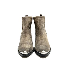 May include: A pair of grey ankle boots with a snakeskin texture. The boots have silver-coloured metal accents on the toes and a black sole. The boots are displayed against a white background.