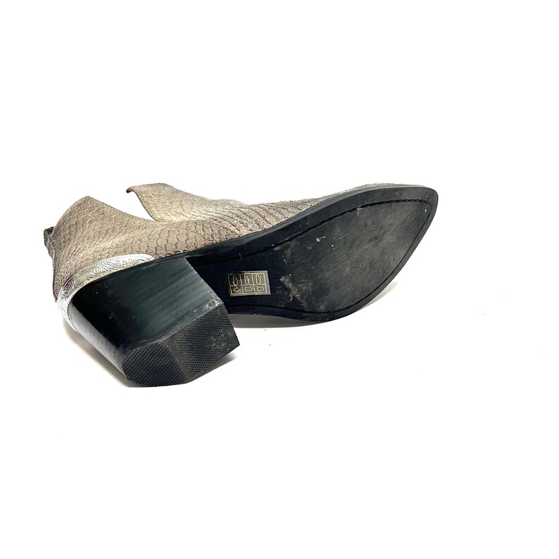 May include: Ankle boots with a snakeskin-effect pattern in grey and beige. The boots have a pointed toe and a block heel with a silver accent. The sole is black.