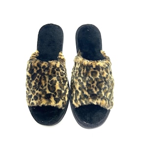 May include: A pair of open-toe slippers with a black sole and a faux fur leopard print design. The top of the slipper is black, and the leopard print is brown and tan.