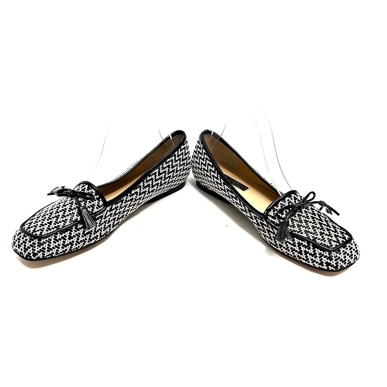 Op de afbeelding: Een paar zwart-wit patronen loafers met een vierkante neus. De schoenen hebben een zwarte leren rand en een kleine strik met een kwastje op de wreef. De schoenen staan tegen een witte achtergrond.