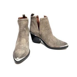 May include: A pair of grey ankle boots with a snakeskin pattern. The boots have a pointed toe with a silver metal cap, a black heel, and a V-shaped cut on the side. The boots are made of a suede-like material.