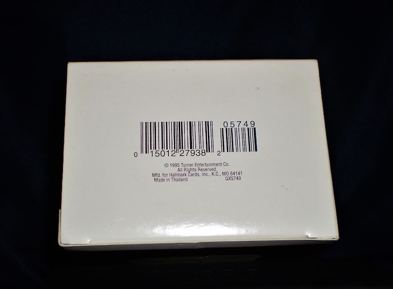 Peut inclure: Une bo&icirc;te blanche avec un code-barres et le texte "05749", "1996 Turner Entertainment Co. All Rights Reserved", "Mid. for Hallmark Cards, Inc., K.C., MO 64141", "Made in Thailand", et "QX5749".