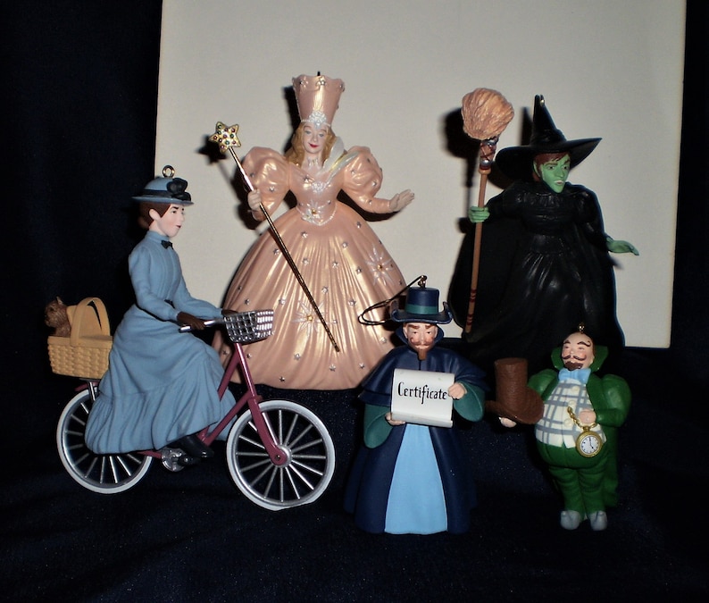 Peut inclure: Un ensemble de sept d&eacute;corations de No&euml;l sur le th&egrave;me du Magicien d'Oz. Les d&eacute;corations repr&eacute;sentent des personnages du film, notamment Dorothy, la M&eacute;chante Sorci&egrave;re de l'Ouest, le Magicien et l'&Eacute;tain. Les d&eacute;corations sont en porcelaine et peintes dans des couleurs vives.