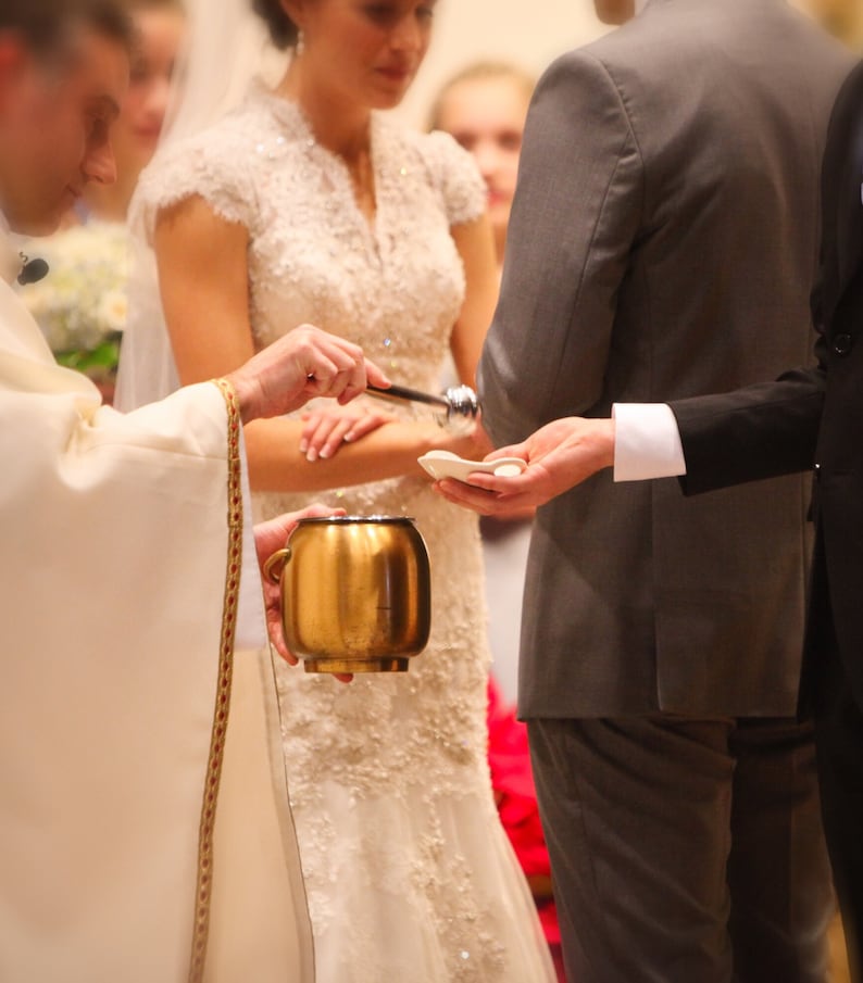 couple having rings blessed using clarey clayworks wedding bowl