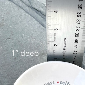 Peut inclure: Bol en c&eacute;ramique blanche d'une profondeur de 2,5 cm. Le bol porte les mots "gentleness" et "self-control" inscrits sur le bord.