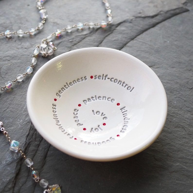 Peut inclure: Un plat &agrave; bijoux en c&eacute;ramique blanche avec les mots "amour, joie, paix, patience, gentillesse, douceur, fid&eacute;lit&eacute; et ma&icirc;trise de soi" inscrits en cercle sur le bord. Des points rouges sont plac&eacute;s entre chaque mot.