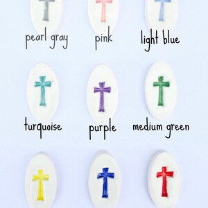 May include: Nine ceramic oval-shaped tiles with a cross design in different colors: pearl gray, pink, light blue, turquoise, purple, medium green, yellow, navy, and red.