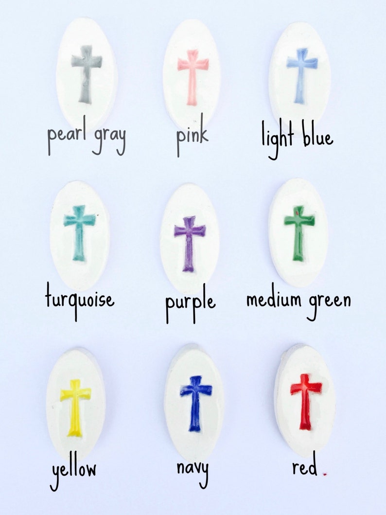 May include: Nine ceramic oval-shaped tiles with a cross design in different colors: pearl gray, pink, light blue, turquoise, purple, medium green, yellow, navy, and red.