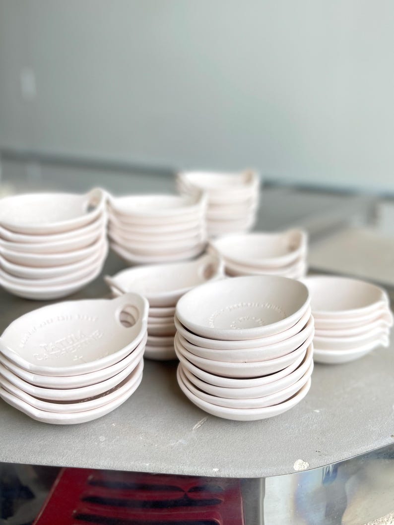 8 short stacks of ceramic bowls sit on top of a kiln.