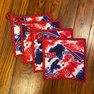 May include: Four red, white, and blue quilted pot holders with a tie-dye pattern and the Buffalo Bills logo.