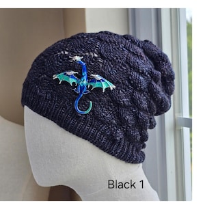 May include: Three knitted beanies in different colors: black, gray, and purple. The black beanie features a blue and green dragon embellishment. Each hat is displayed on a mannequin head. The text "Black 1", "Gray 1", and "Gray 2" are visible.