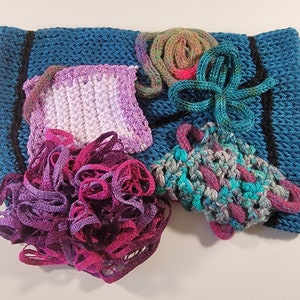 May include: A teal crocheted square with a black border, featuring a purple and white crocheted square, a teal and purple crocheted piece, a pile of purple and pink yarn, and a teal and pink yarn ball.