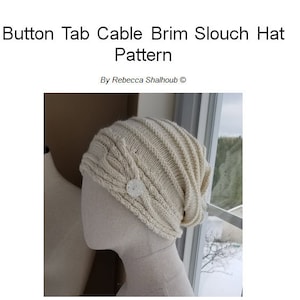 May include: A white knitted slouch hat with a cable knit pattern and a button detail. The hat is on a white mannequin head.