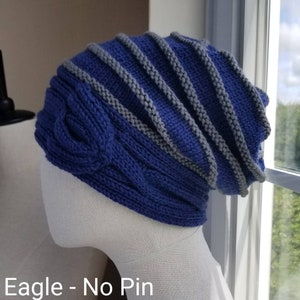May include: A blue and gray knitted beanie with a cable knit pattern. The beanie is on a white mannequin head. The text "Eagle - No Pin" is visible below the beanie.