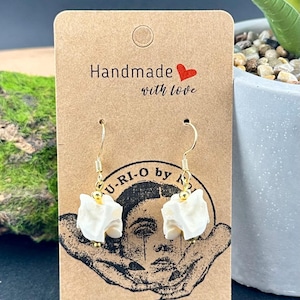 May include: White, textured earrings with gold-colored hooks hang from a brown card that reads "Handmade with love." The card also features a graphic and the text "U-RI-O by K".