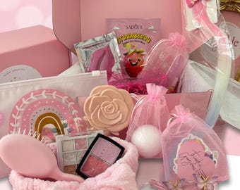 Peut inclure: Une boîte cadeau rose contenant divers articles de beauté et accessoires, dont une brosse à cheveux rose, un bandeau en peluche avec un nœud, un poudrier en forme de rose, un masque facial à la fraise, une petite palette de fards et des pinces.
