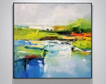 Puede incluir: Pintura abstracta de paisaje con marco negro. La obra presenta una escena vibrante con campos verdes, amarillos y naranjas, una masa de agua azul y un cielo nublado. La pintura utiliza pinceladas gruesas.