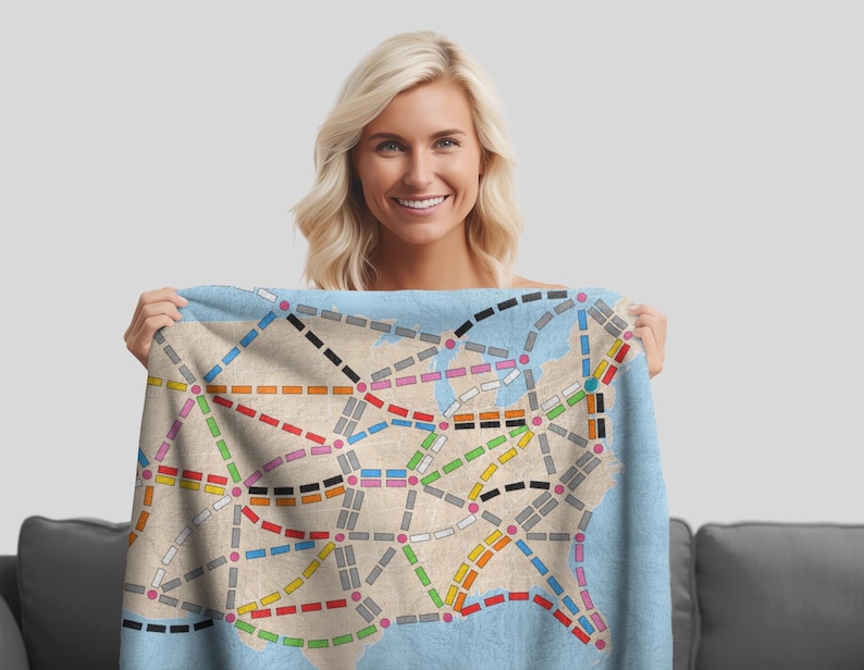 May include: A blue throw blanket with a map of the United States printed on it. The map shows the major cities and highways in the country. The blanket is being held by a person.