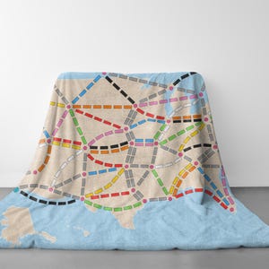 May include: A blue and beige throw blanket with a map of the United States printed on it. The map shows the major cities and highways in the country. The blanket is made of soft, comfortable fabric and is perfect for snuggling up on the couch.