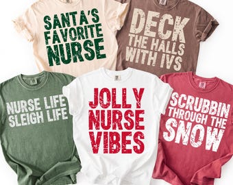 Könnte beinhalten: Fünf T-Shirts mit festlichen Slogans für Krankenschwestern. Die Shirts sind in verschiedenen Farben erhältlich, darunter Beige, Braun, Grün, Weiß und Rot. Der Text lautet "Santa's Favorite Nurse", "Deck the Halls with IVs", "Nurse Life Sleigh Life", "Jolly Nurse Vibes" und "Scrubbin' Through the Snow".